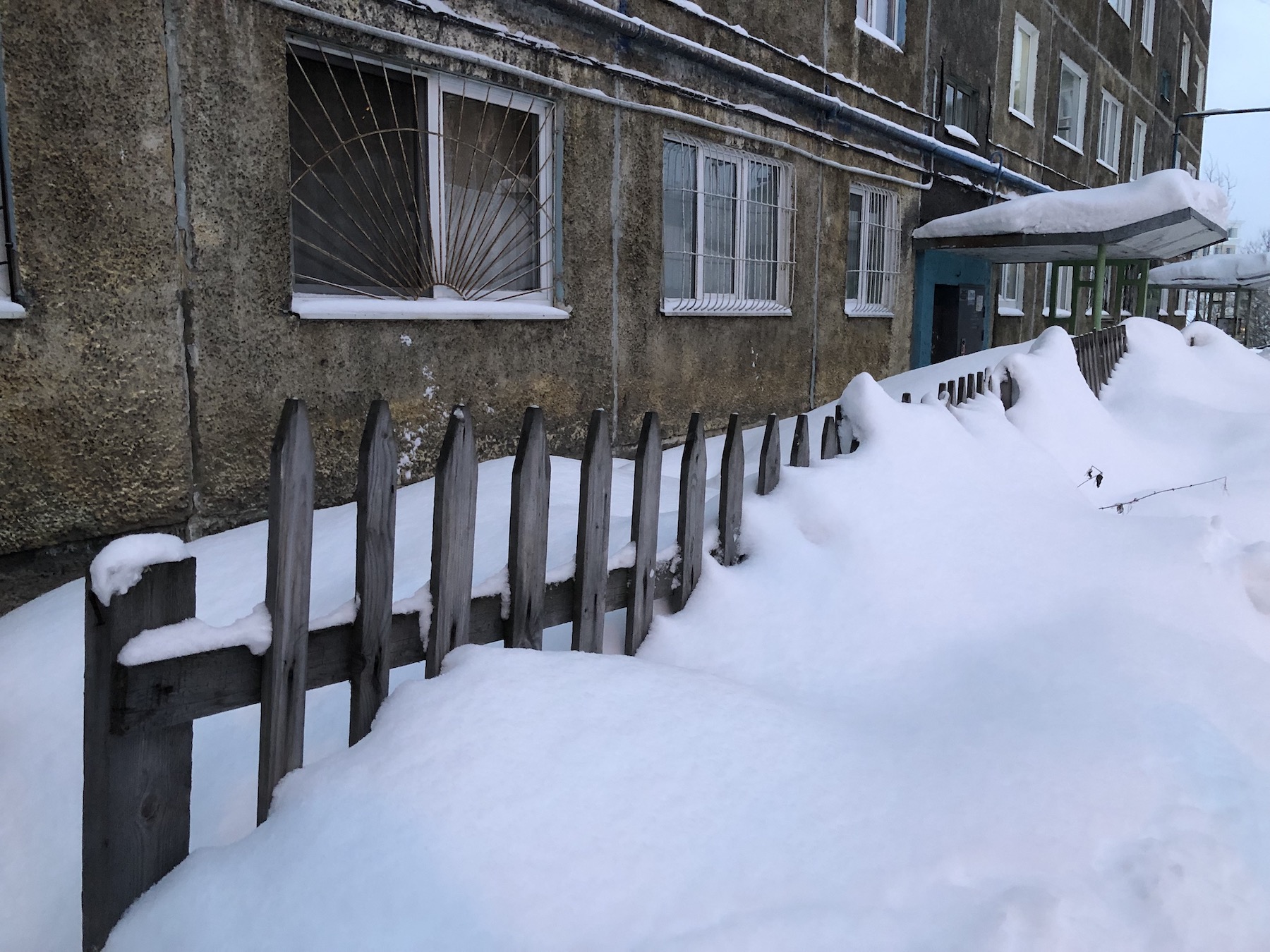 Деревянный забор у панельного дома в Мурманске
